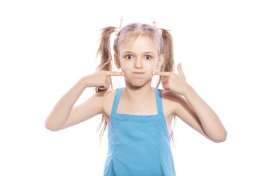 Beyaz izole zemin üzerinde mavi elbiseli Genç yedi yaşında esmer kız. Yüzünde onun yanakları, komik duygular üflüyor