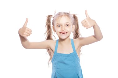 Beyaz izole zemin üzerinde mavi elbiseli Genç yedi yaşında esmer kız. O yüzündeki başparmak yukarıya hareketi elleri, gülümseyen ve mutluluk ve sevinç duygular ile yapmak