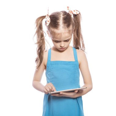 Beyaz izole zemin üzerinde mavi elbiseli Genç yedi yaşında esmer kız. O tablet, nasıl kullanılır, yüzünde düşünceli duygular anlamaya çalışan tutar