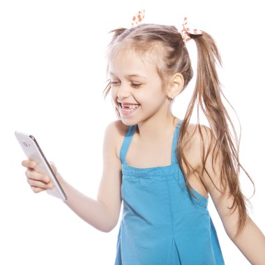 Beyaz izole zemin üzerinde mavi elbiseli Genç yedi yaşında esmer kız. O yüzündeki mobil telefon, eğlenceli ve gülümseme duygularını üzerinde selfie yapar