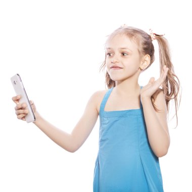 Beyaz izole zemin üzerinde mavi elbiseli Genç yedi yaşında esmer kız. Gülümseyen, telefonunu kullanarak video konferans tarafından konuşurken yüzünde mutluluk duyguları