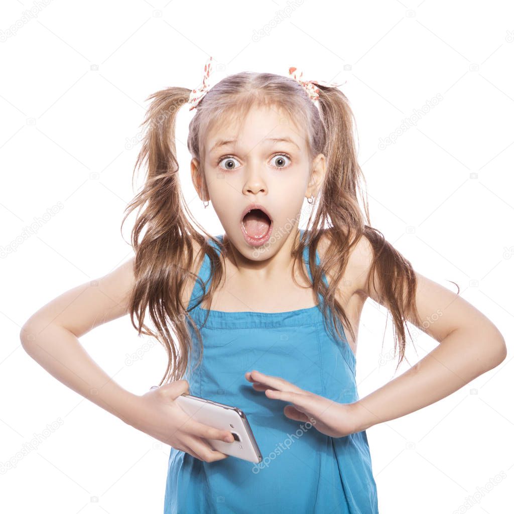 Young seven years old brunette girl in blue dress on a white isolated background. Amazement, surprise emotions on her face. Talking on the phone