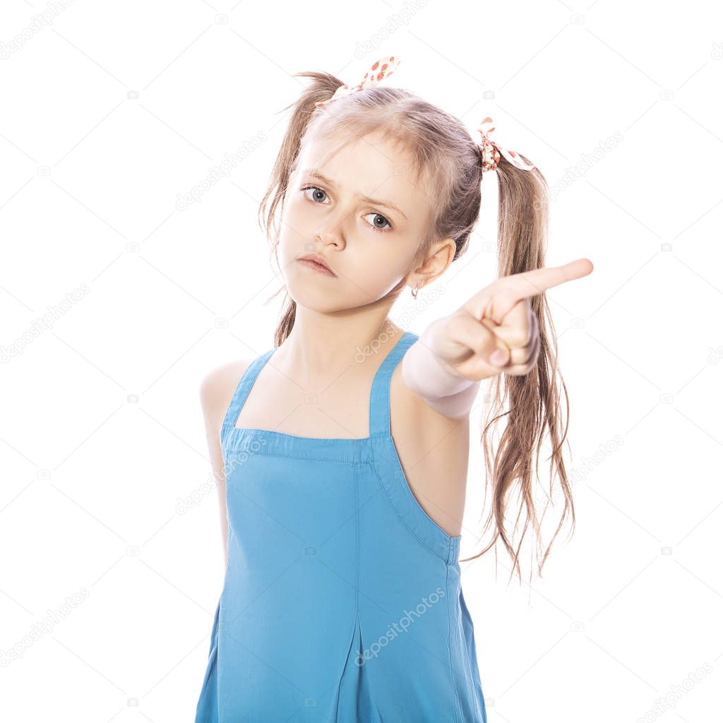 Young seven years old brunette girl in blue dress on a white isolated background. Angry, unhappy, sad emotions on her face