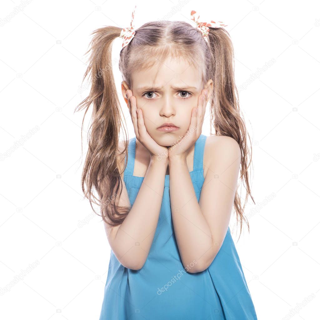 Young seven years old brunette girl in blue dress on a white isolated background. Unhappy, sad emotions on her face