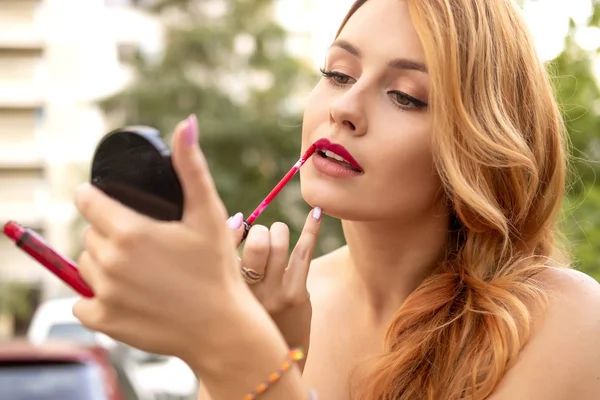 Beautiful plus size woman painting her lips wih red lipstick, lo — Stock Photo, Image