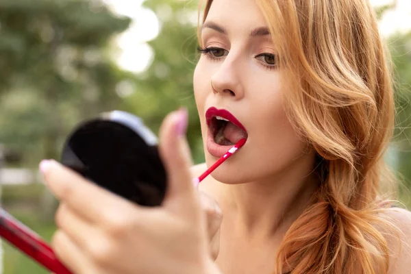 Beautiful plus size woman painting her lips wih red lipstick, lo — Stock Photo, Image