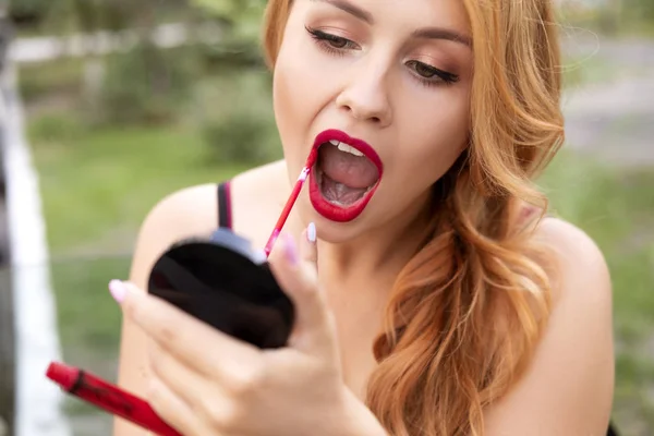 Beautiful plus size woman painting her lips wih red lipstick, lo — Stock Photo, Image