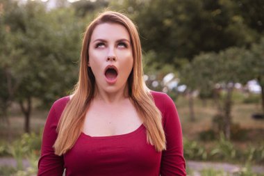 Kadın orgazm taklidi yapıyor. Sıradan ama seksi kıyafetler giyip parkta dikiliyor. Altılık boşluklu yaz akşamı portresi.