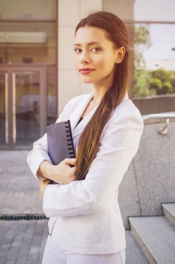 Beyaz takım elbiseli güzel esmer bir iş kadını. Elinde bir dosya dolusu belge var. Boşluğu kopyala