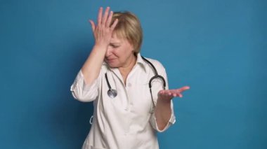 Beyaz önlüklü, mavi arka planda, Kafkasyalı, yaşlı bir doktor. Steteskop takıyor ve 