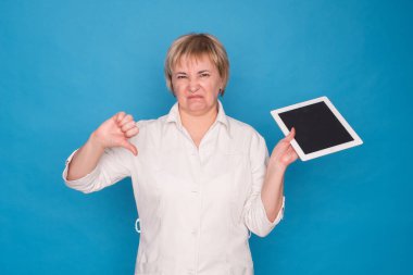 Beyaz önlüklü, mavi arka planda tableti olan yaşlı, beyaz bir doktor. Duygusal Portre.