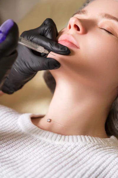 美容师医生为一位在诊所的妇女做注射手术 她戴着黑色的光泽和面具 拿着注射器和针头 — 图库照片