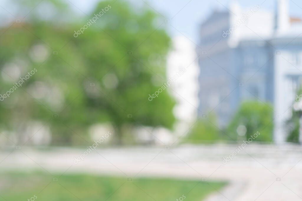 Blurred view on a park alley. Background unfocused image with bokeh on sunny summer day. Space for text