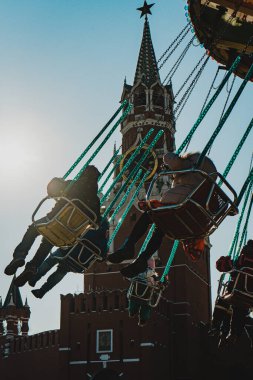 Çocuklar kırmızı bir atlıkarıncaya biniyorlar.