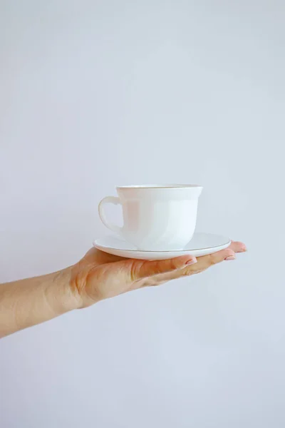white mug with a cup in hand on a white wall background