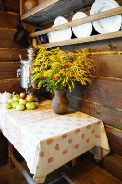 Kil vazo, kır çiçekleri, semaver ve bahçe elmaları masanın üzerinde.