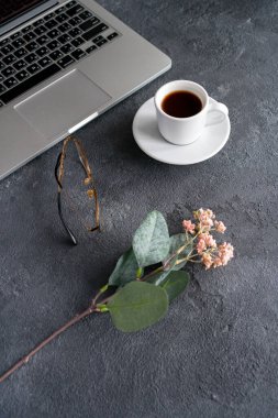 Bir kupa kahve siyah bir günlükte duruyor, sonra bir dizüstü bilgisayar ve çiçek yalan söylüyor.