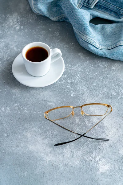 a coffee mug stands on notebooks, a laptop stands next to it and glasses lie