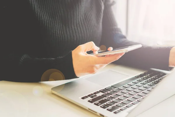 Bir kız elinde bir telefon, yanında bir laptop duruyor ve gözlük yalan söylüyor.