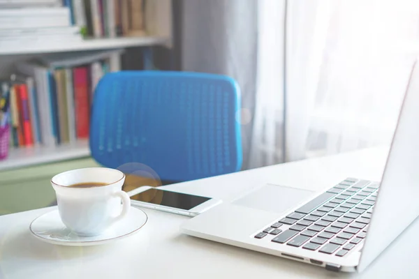 coffee mug and laptop stand on the desktop on a sunny day