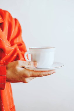 Kırmızı ceketli kız elinde bir kupa kahve tutuyor.