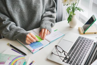 Günlüğünü karıştıran bir kız, yakınlarda bir dizüstü bilgisayar duruyor ve gözlükler yalan söylüyor.