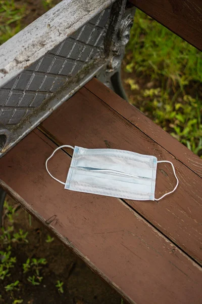 a protective mask from the virus lies on a bench in the park