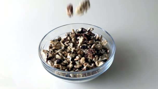 Core of walnuts are poured into glass bowl on the table. Slow motion. — Stock Video