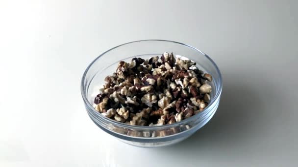 De kern van walnoten wordt op tafel in een glazen schaal gegoten. Langzame beweging. — Stockvideo