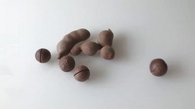 Masaya dağılmış Macadamia fındıkları ve olgun demirhindi meyveleri. Yavaş çekim.