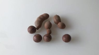 Masaya dağılmış Macadamia fındıkları ve olgun demirhindi meyveleri. Yavaş çekim.