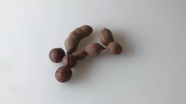 Masaya dağılmış Macadamia fındıkları ve olgun demirhindi meyveleri. Yavaş çekim.