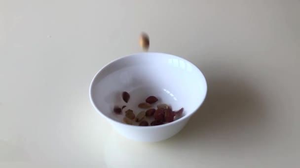 Erdnüsse werden in eine Glasschale auf dem Tisch gegossen. Zeitlupe. — Stockvideo