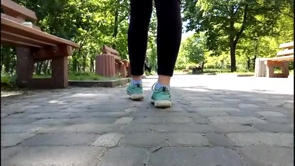 Detalhe de mulheres pés andando pela cidade. Pernas femininas andam em tênis verdes ao longo de um caminho de pedra suja . — Vídeo de Stock