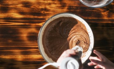 Çırpılmış çikolata hamuru. El, bir turtanın malzemelerini bir kaseyle karıştırıyor..