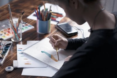 - Sanat. Yaratılış. Yakın plan. Kız albümde suluboya resim çiziyor.