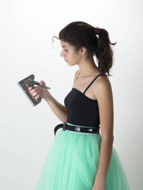 Açık renk elbiseli bir kız elindeki zımbaya bakar.