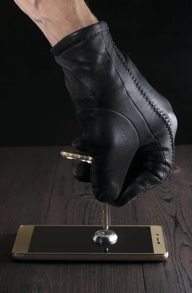 Die Hand eines Angreifers in einem schwarzen Handschuh öffnet das Schloss eines Smartphones mit einem Schlüssel. das Konzept des Schutzes persönlicher Daten. Schutz durch Verschlüsselungsschlüssel. — Stockfoto