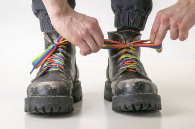 Hands tied rainbow laces on hard black boots clipart