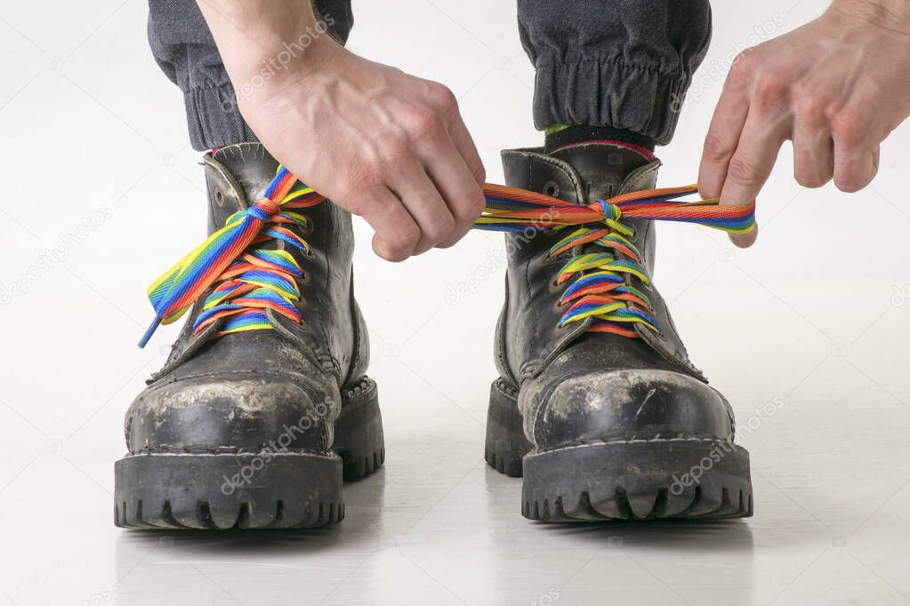 Hands tied rainbow laces on hard black boots