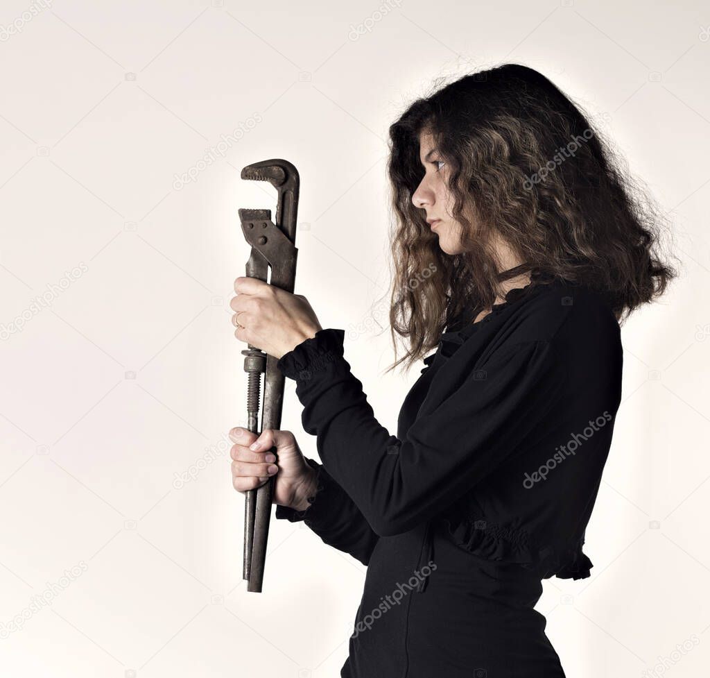 The girl holds a large adjustable wrench in her hands and looks at him. Text Slide