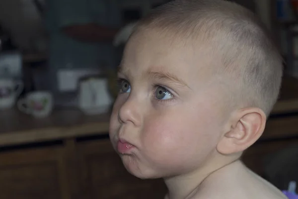 Schattig blond kind eet in de keuken, komkommer sap stroomt op de wangen — Stockfoto