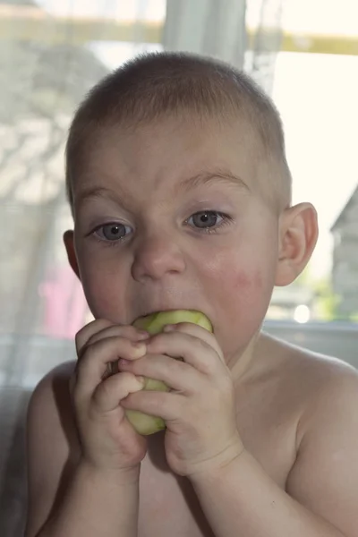 Lindo bebé rubio comiendo un gran jugo de pepino que fluye por sus mejillas —  Fotos de Stock