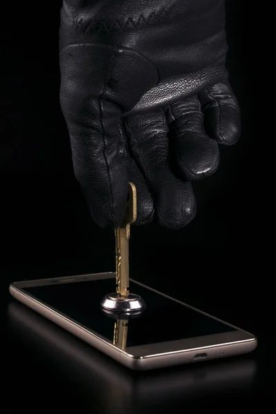 Ręka napastnika w czarnej rękawiczce otwiera zamek na smartfonie kluczem. Koncepcja ochrony danych osobowych. Ochrona klucza szyfrowania. — Zdjęcie stockowe