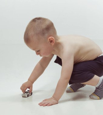 Sarışın çocuk yerde küçük bir oyuncak arabayla oynuyor.