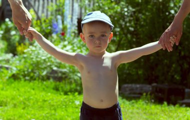 Mutlu genç aile bahar doğasında eğleniyor, yeşil gözlü parlak çocuk ebeveynlerinin elini tutuyor.