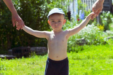Mutlu genç aile bahar doğasında eğleniyor, yeşil gözlü parlak çocuk ebeveynlerinin elini tutuyor.