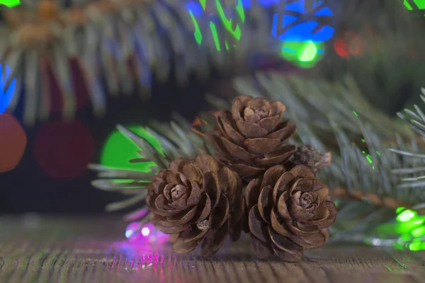 Σύνθεση από μια νεκρή φύση για τις γιορτές των Χριστουγέννων και της Πρωτοχρονιάς. Κουκουνάρια, γιρλάντες και κεριά, καθώς και χριστουγεννιάτικο δέντρο με χριστουγεννιάτικες διακοσμήσεις — Φωτογραφία Αρχείου