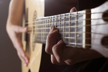 Akustik gitar çalan genç bir kız. Manikürlü parmaklar perdelerde