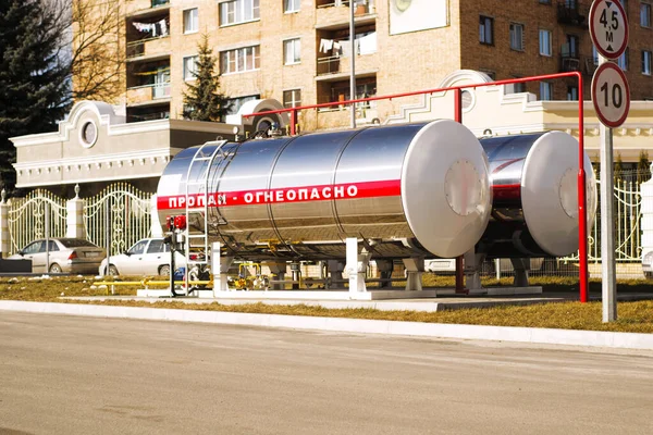 Kentte bir benzin istasyonunda ayna cilalı bir tank. Rus propanındaki yazıtlar yanıcı. Çok katlı bir binanın avlusundaki büyük propan tankı, arka plandaki ev ve aşağıdaki metin için bir yer.